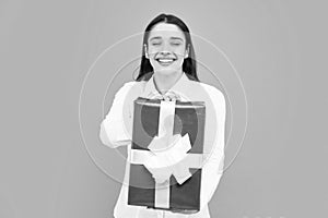 Portrait of a happy smiling girl holding present box and isolated over gray background.