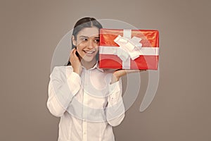 Portrait of a happy smiling girl holding present box and  over gray background.