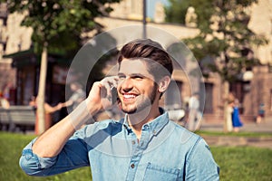 Portrait of happy smiling guy talking on phone in the park