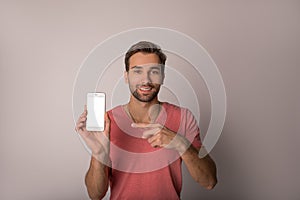 Portrait of a happy smiling handsome bearded hipster guy holding in hand mobile phone