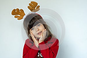 Portrait of happy smiling kid in a red knitted pullover with a Santa hat on head isolated on white background.