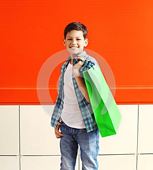 Portrait happy smiling little boy teenager with shopping bag in city