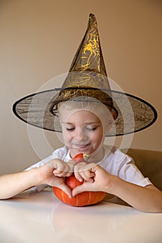 Portrait of a happy smiling little boy in a witch`s hat holding a pumpkin. Childhood, Halloween, decoration concept