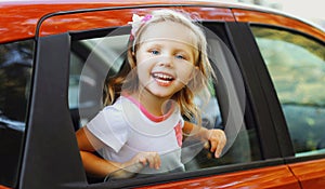 Portrait of happy smiling little child passenger sitting in red car