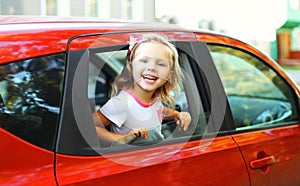 Portrait happy smiling little child sitting in red car