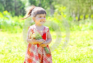 Portrait happy smiling little girl child with flowers in summer