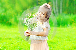 Portrait happy smiling little girl child holding bouquet flowers in her hands in spring