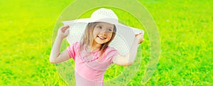 Portrait of happy smiling little girl child wearing summer straw hat in sunny day