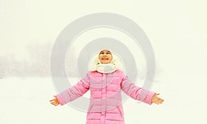 Portrait of happy smiling little girl child in winter over snowy background