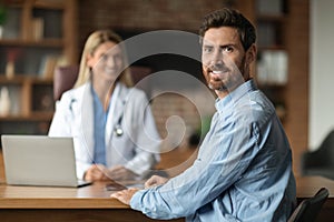 Portrait Of Happy Smiling Male Patient Sitting At Doctor's Office