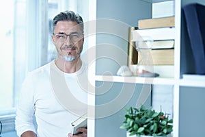 Portrait of happy smiling man reading book at home in glasses