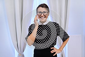 Portrait of happy smiling mature business woman in glasses talking on phone