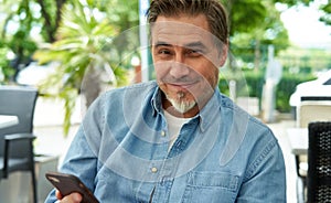 Portrait of happy smiling mid adult man with phone