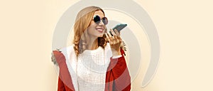 Portrait of happy smiling modern young woman holding smartphone using voice command recorder, assistant or takes calling and