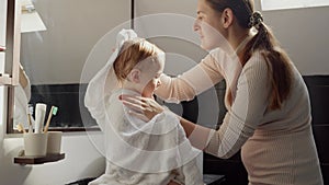 Portrait of happy smiling mother and baby boy covered in towel hugging after washing in bath.