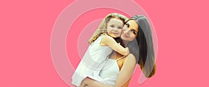 Portrait of happy smiling mother hugging little girl child on pink background