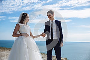 Portrait of happy smiling newlyweds couple on mountain with ocean background