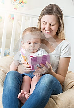Portrait of happy smiling oyung mother reading book to her baby