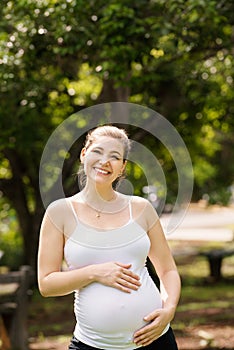 Portrait of happy and smiling pregnant woman in park