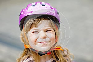 Portrait of happy smiling preschool girl with bycicle helmet on head. Cute toddler child. Safe bike driving with photo