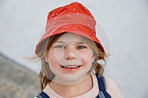 Portrait of happy smiling preschool girl outdoors. Little child with blond hairs looking and smiling at the camera
