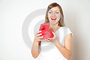 Portrait of a happy smiling pretty girl opening a red present box on the white background.