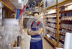 Portrait of happy smiling sales assistant standing in one of aisles at hardware store