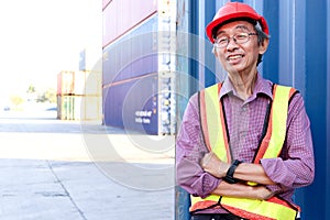 Portrait of happy smiling senior elderly Asian worker engineer wearing safety vest and helmet, standing with arms crossed with