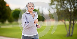 Portrait of happy smiling senior lady in sportswear jogging in early morning outside in city park