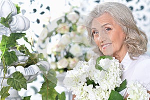 Portrait of happy smiling senior woman posing with flowers