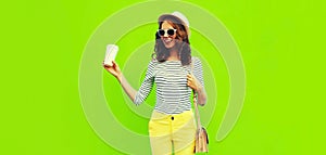 Portrait of happy smiling stylish young woman with coffee cup wearing handbag, striped t-shirt and summer straw round hat on green