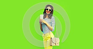 Portrait of happy smiling stylish young woman with coffee cup wearing handbag, striped t-shirt and summer straw round hat on green