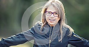 Portrait of a happy smiling teenage girl with dental braces and glasses