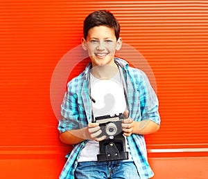 Portrait happy smiling teenager boy with retro camera on a red