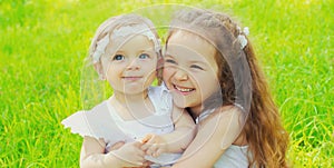 Portrait happy smiling two little sister girls children together in summer park