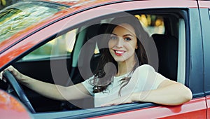 Portrait of happy smiling woman driver behind wheel red car