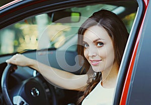 Portrait of happy smiling woman driver behind wheel red car