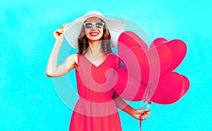 Portrait happy smiling woman holds pink heart shaped air balloons on blue background