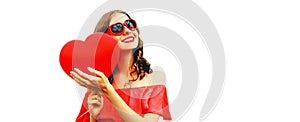 Portrait of happy smiling woman with red heart shaped balloon wearing sunglasses isolated on white background