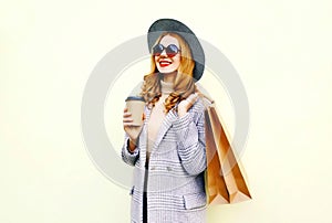 Portrait happy smiling woman with shopping bags, holding coffee cup, wearing pink coat, round hat