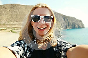 Portrait of happy smiling woman stretching hand for taking selfie over sea