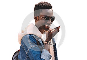 Portrait of happy smiling young african man holding smartphone using voice command recorder, assistant or takes calling, looking