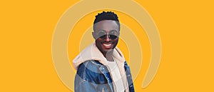 Portrait of happy smiling young african man looking at camera wearing jeans jacket isolated on yellow background