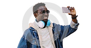 Portrait happy smiling young african man taking selfie by smartphone listening to music in headphones isolated on a white