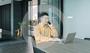 Portrait of happy smiling young business Asian, Chinese man person using laptop computer, working, and talking on smart mobile