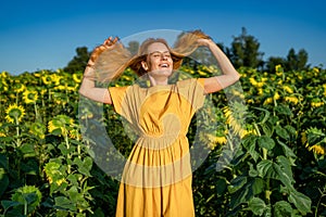 Portrait of happy smiling young caucasian red-haired woman in a sunflower field