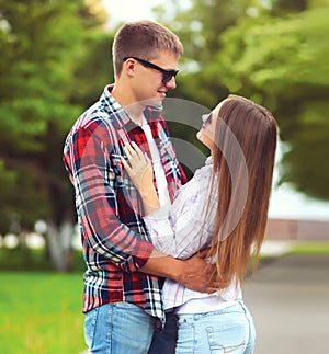 Portrait of happy smiling young couple hugging and looking at each other in summer city park