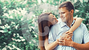 Portrait of happy smiling young couple in love in blooming spring garden park