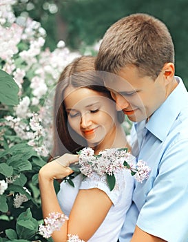 Portrait of happy smiling young couple in love in blooming spring garden park