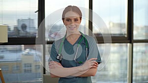 Portrait of happy smiling young female doctor wearing blue green uniform and stethoscope looking at camera.